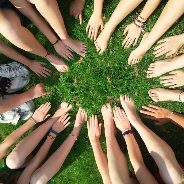 Hände zu einem Kreis auf einer Wiese gelegt, die Gemeinschaft und unsere Gemeinden in Sendling, Thalkirchen und im Westend signalisieren
