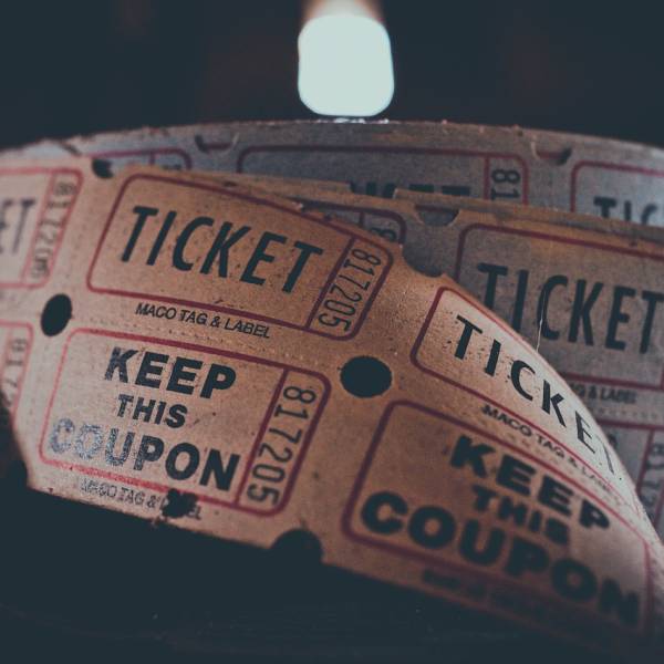 Tickets aus Papier für eine Veransaltung oder ein Konzert an einer Rolle vor dunklem Hintergrund