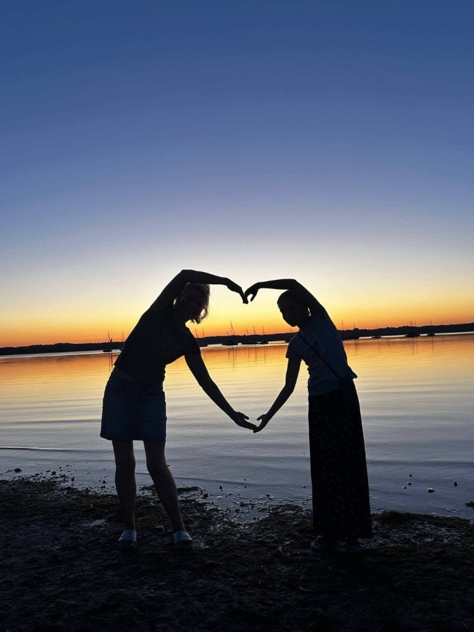 Menschen machen ein Herz am See im Sonnenuntergang